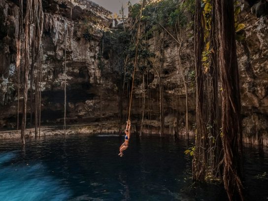 Een vrouw slingerend aan een touw in de Cenote Oxman in Valladolid, Mexico.