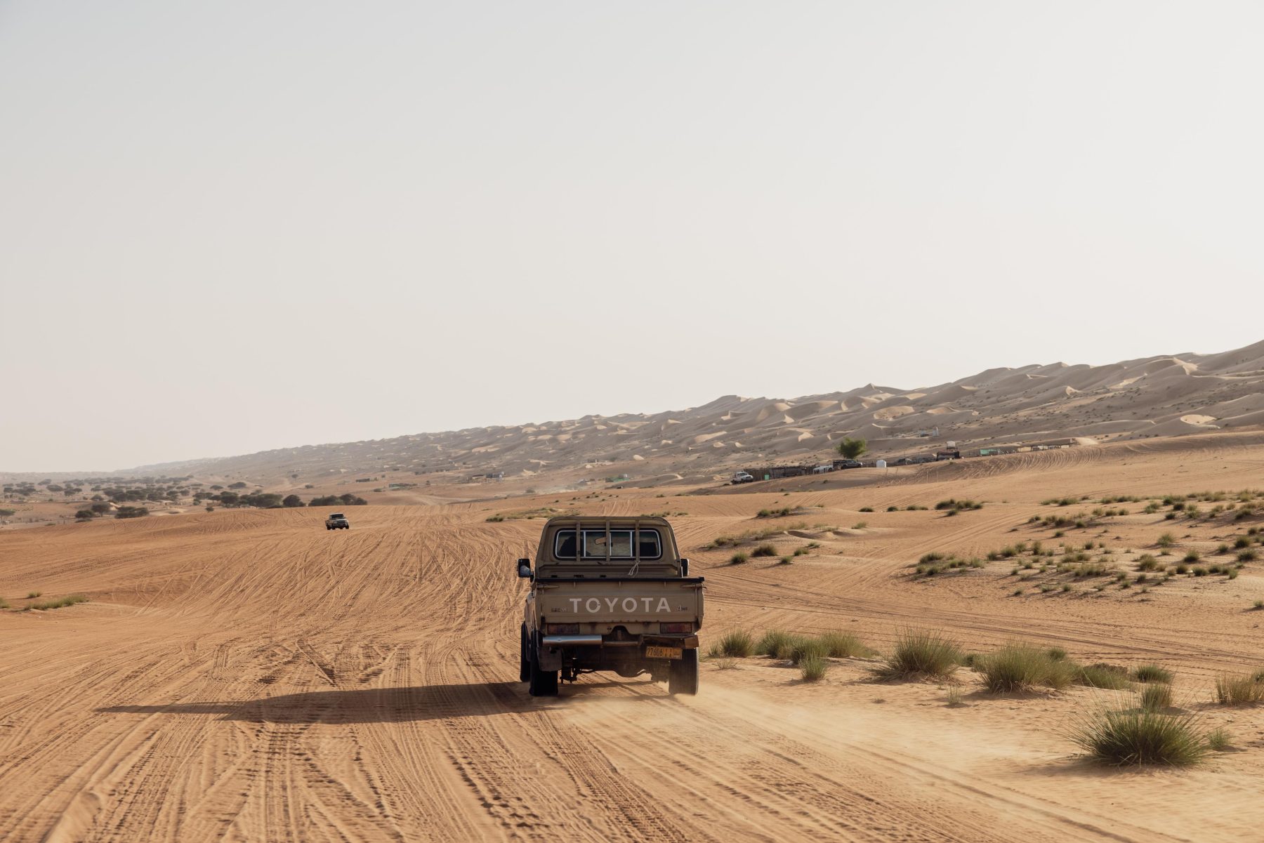 Een auto rijdend door de woestijn in Oman.