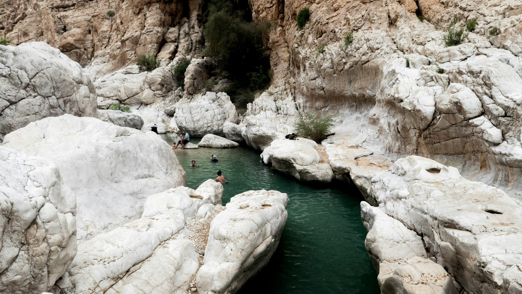 Mensen zwemmend in één van de natuurlijke zwembaden van Wadi Bani Khalid.