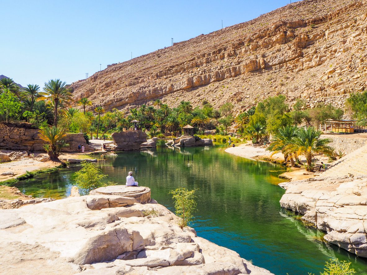 Persoon zittend op een rots in Wadi Bani Khalid.