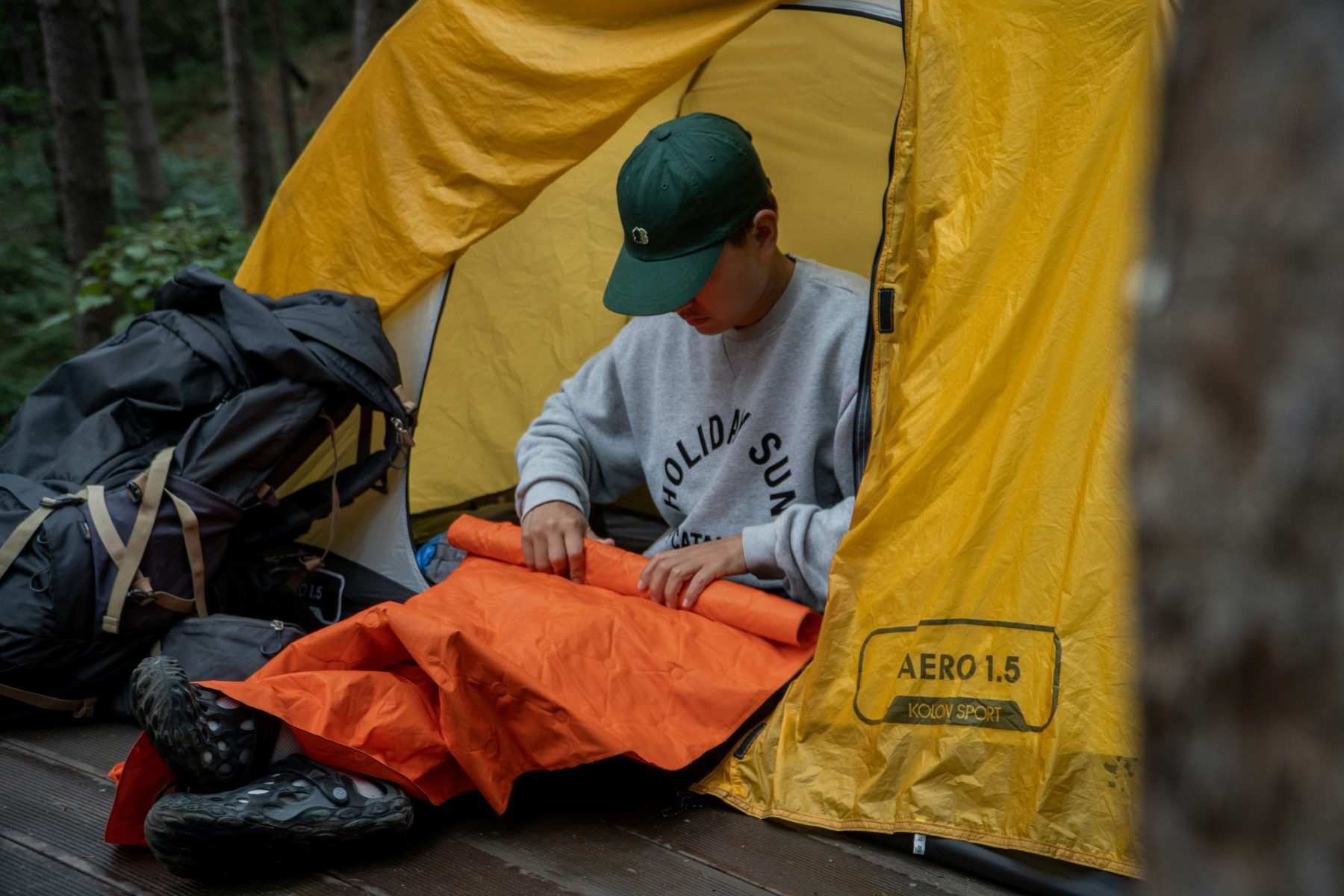 Een man zittend in een tent midden in de natuur.