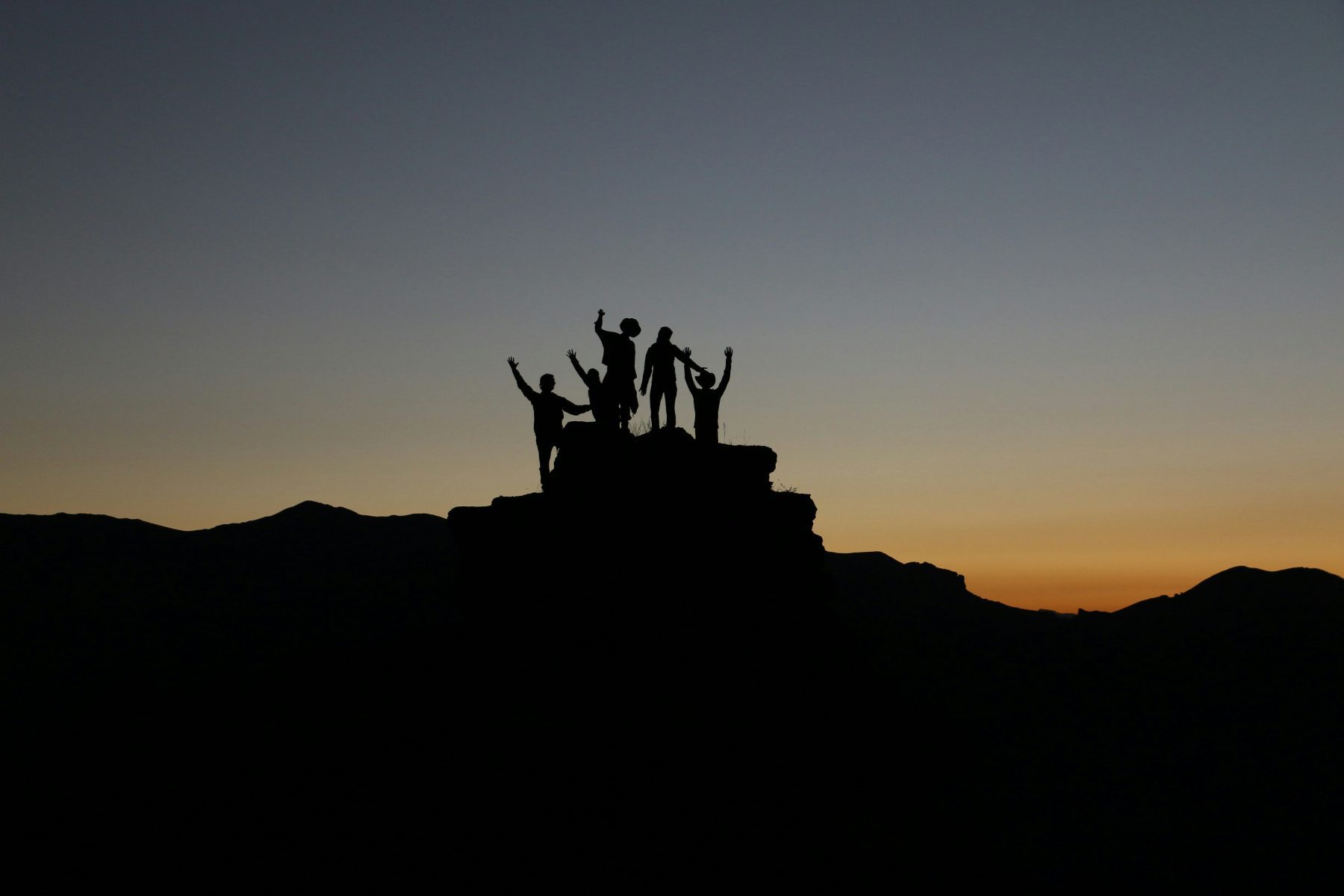 De silhouet van mensen op hoogland tijdens zonsondergang.