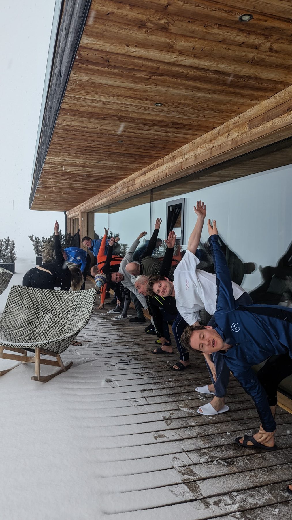 mensen doen yoga oefeningen op een vlonder in de sneeuw