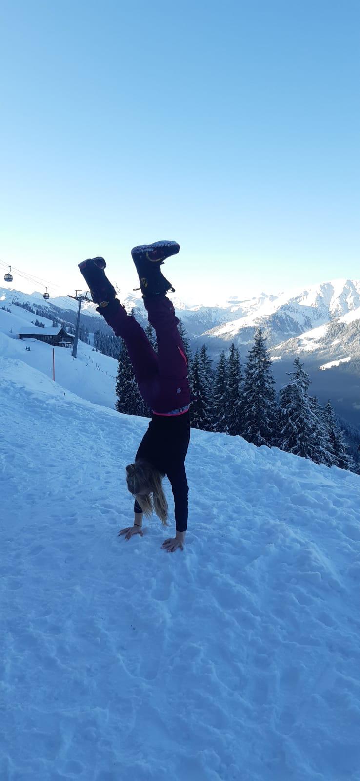 vrouw doet handstand in de sneeuw