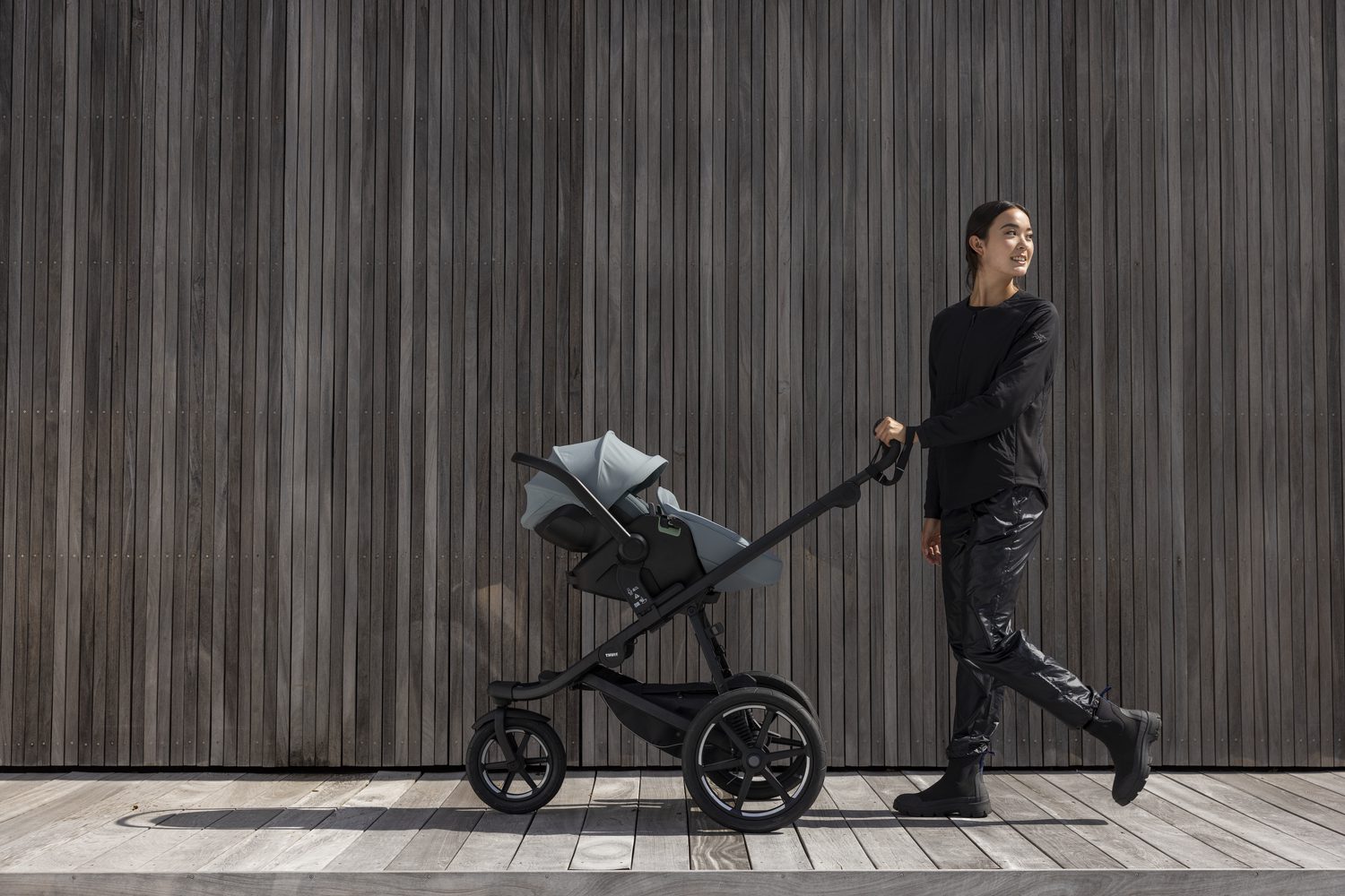 Een vrouw loopt met een Thule Urban Glide 3 kinderwagen en Thule Maple baby-autozitje erop.