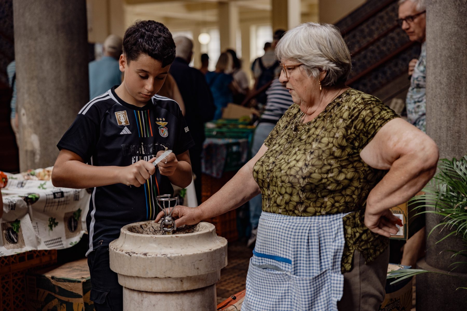 Een jonge jongen en een vrouw zijn samen bezig met het snijden van eten op een lokale markt in Funchal Madeira.