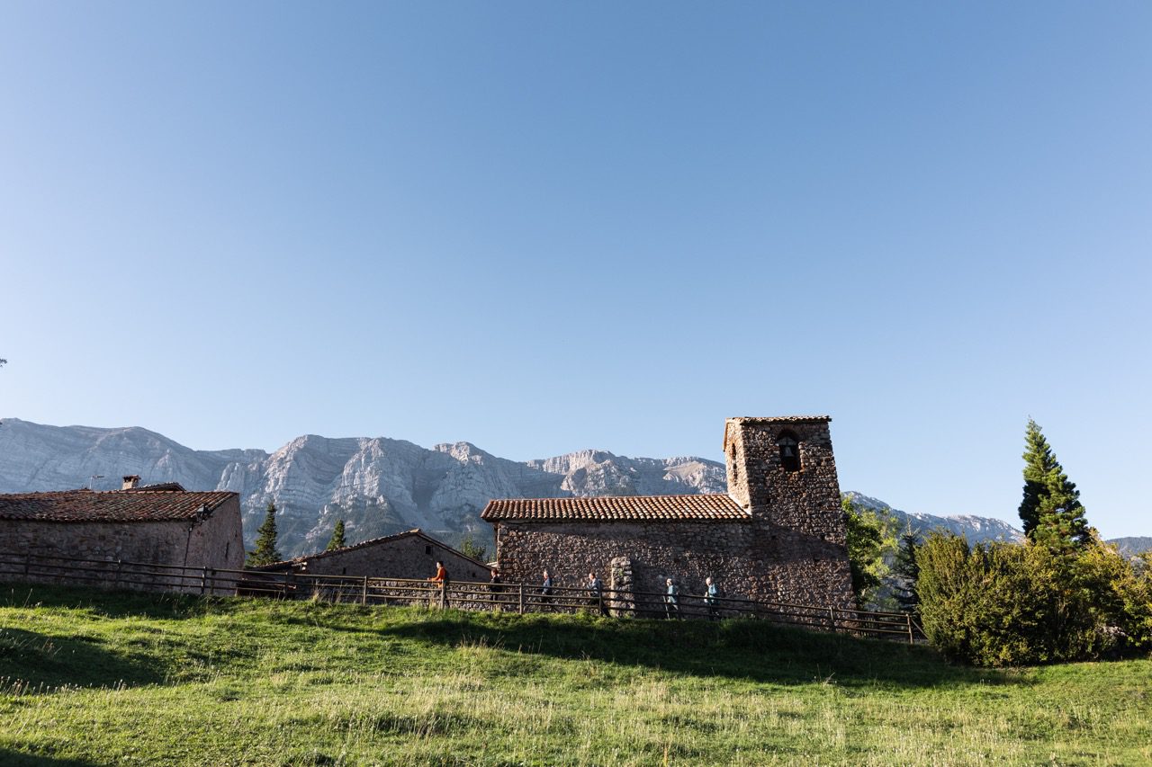 Mensen hiken langs stenen gebouwen midden in de Catalaanse Pyreneeën.