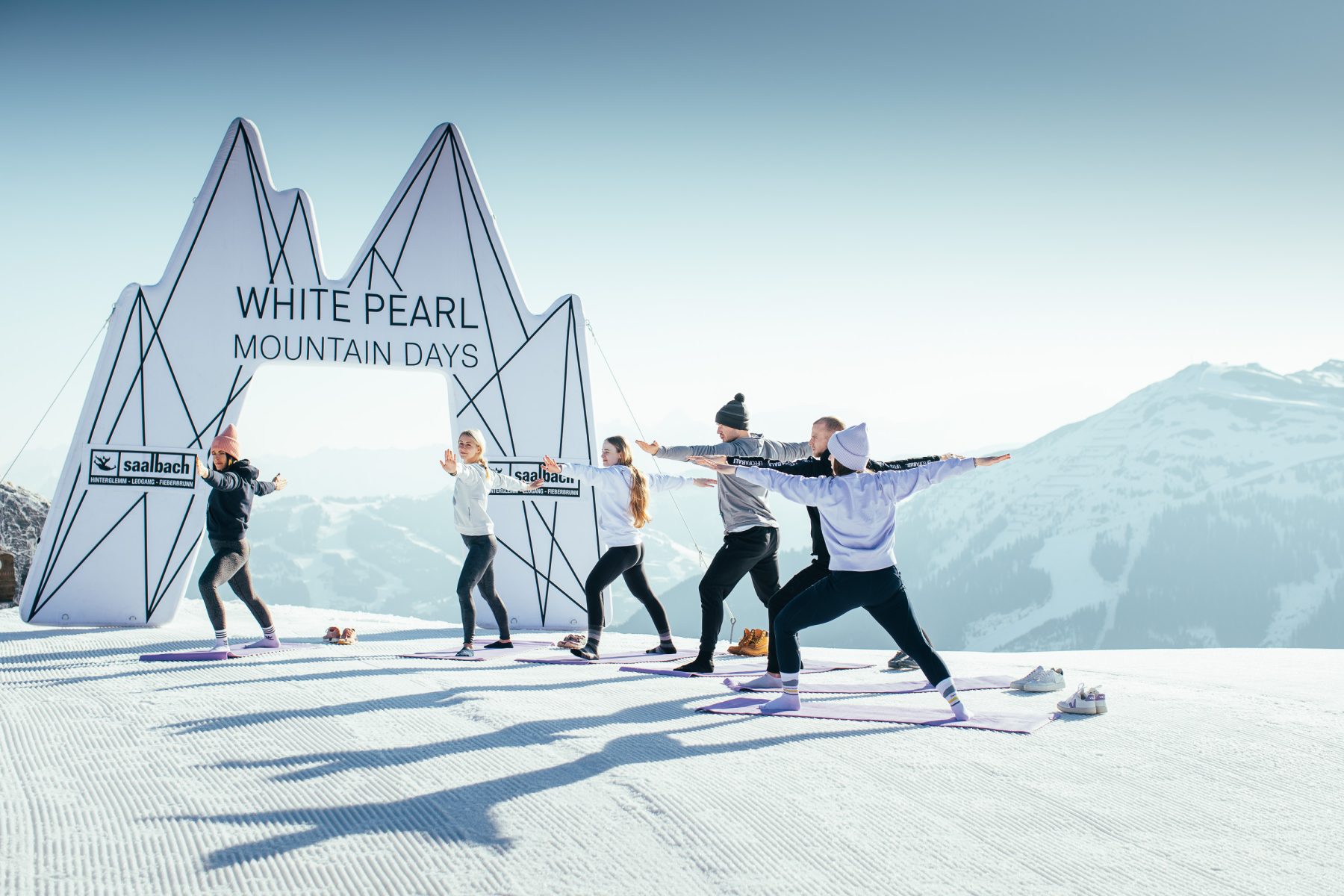 Een groep mensen tijdens een yogasessie op een besneeuwde berg tijdens de White Pearl Mountain Days.