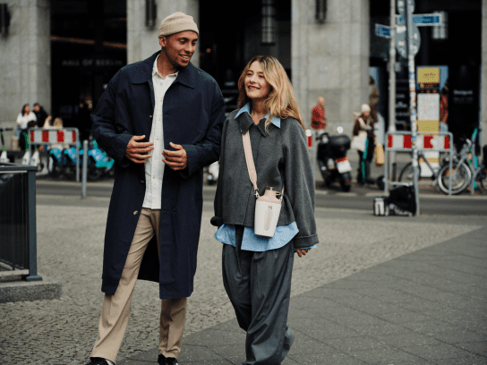 Een man en vrouw wandelend door een stad terwijl de vrouw de Stanley 1913 Cross Bottle in de kleur Rose Quartz omheeft.