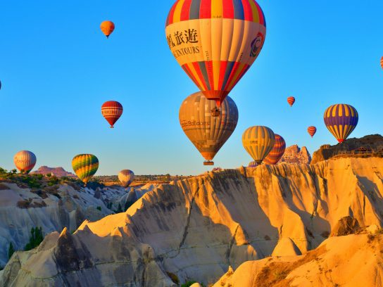 Luchtballonnen zwevend boven een rotsformatie in Cappadocië, wat de bestemming van de Cappadocia Trail is.