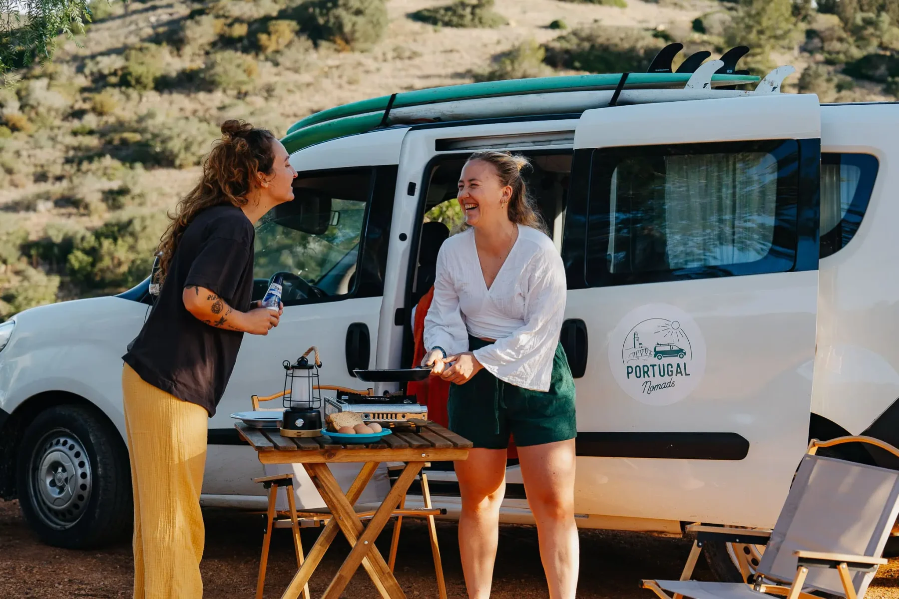 Twee vrouwen staan te koken voor een minivan tijdens Portugal Nomads.