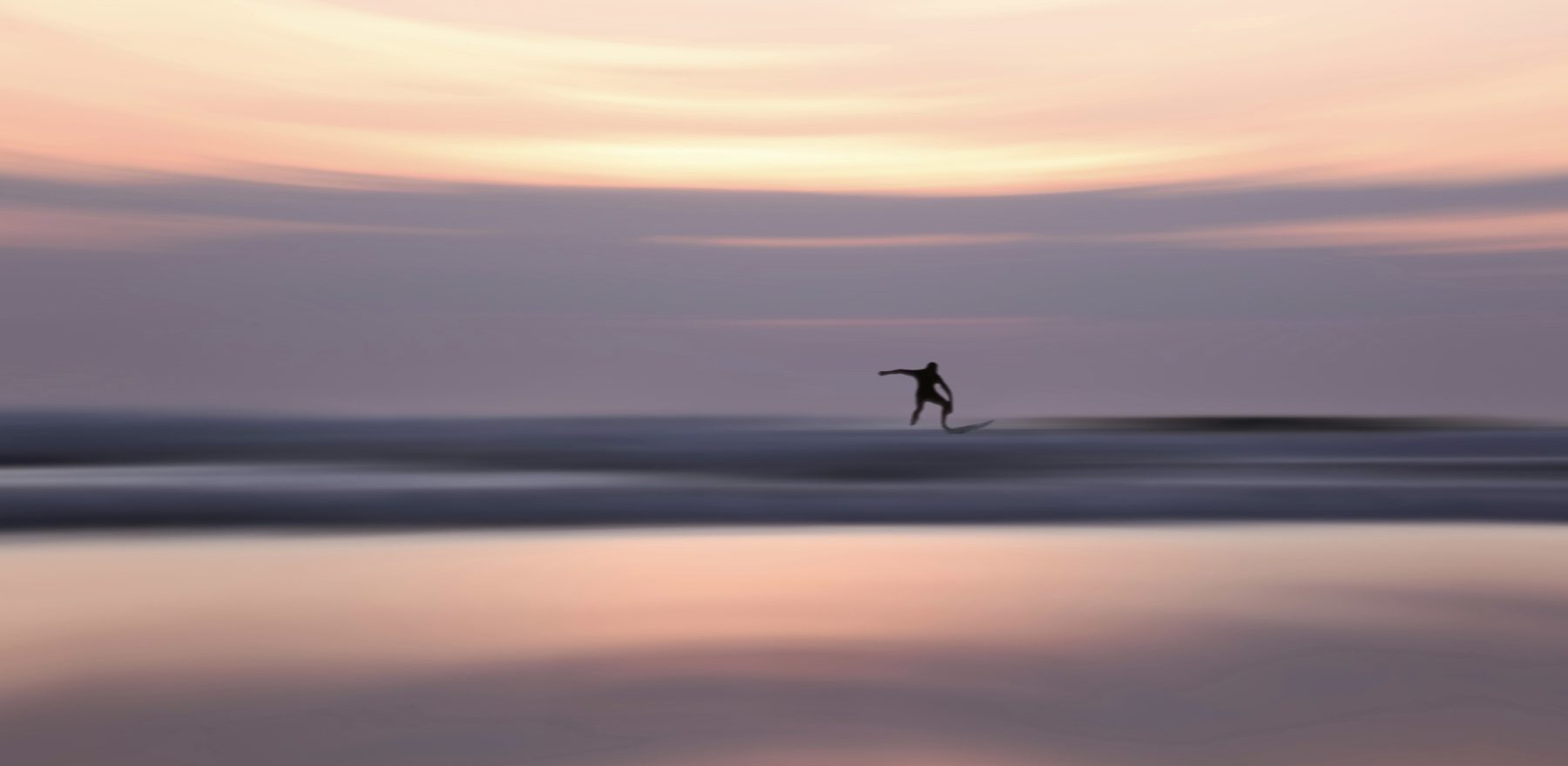 Een wazige foto van een persoon op een surfplank in de zee bij Biscarrosse, wat één van de locaties is van Enter The Wave.