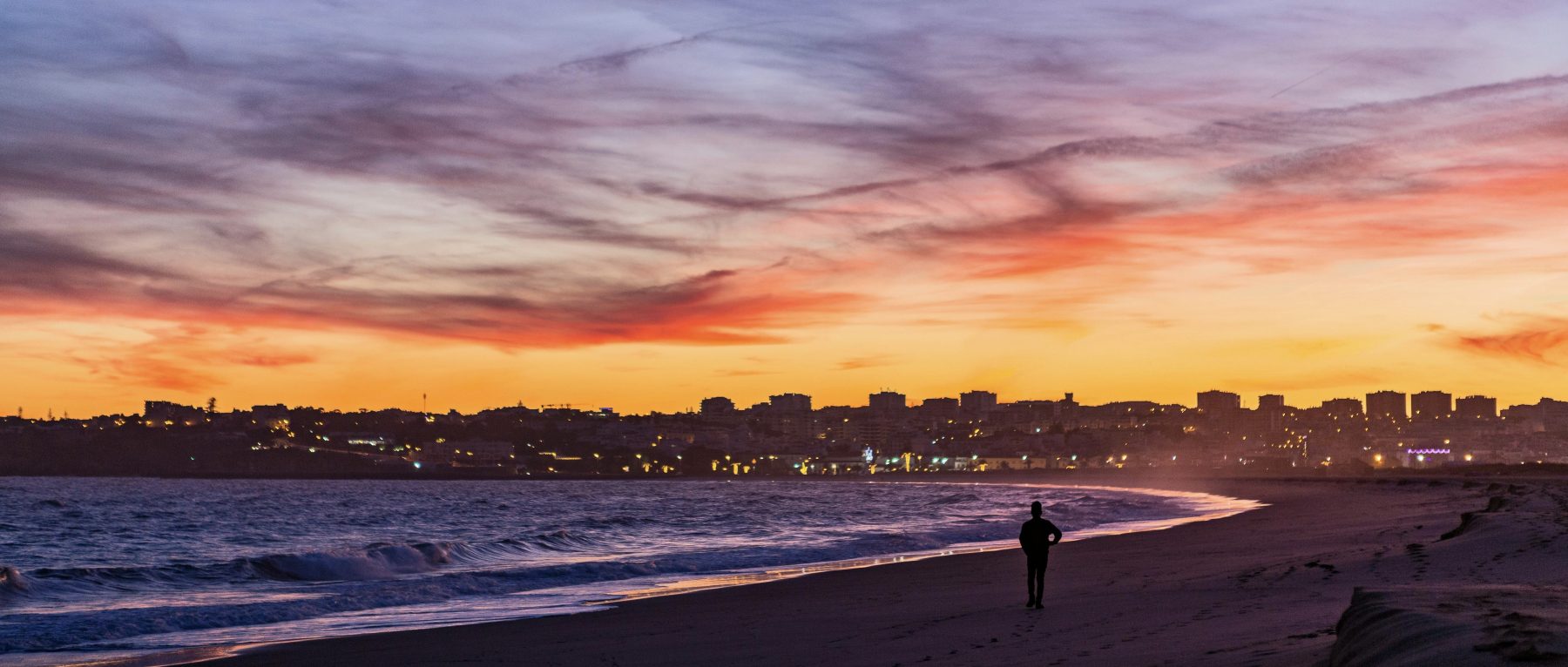 Een persoon wandelt tijdens zonsondergang langs een kustlijn in Lagos.