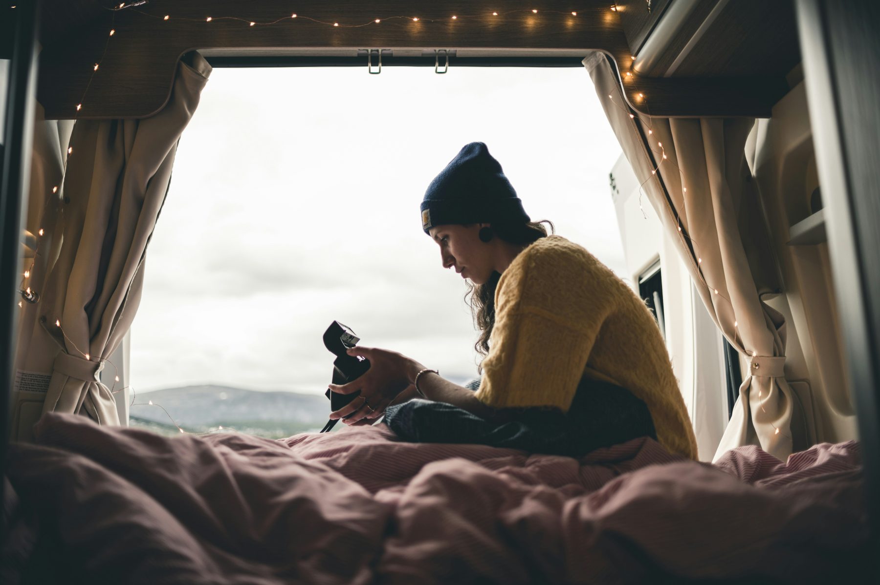 Een vrouw in een camper  in Noorwegen met uitzicht op een mistig landschap.