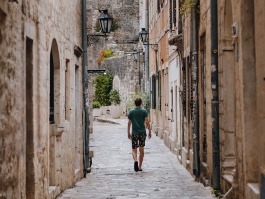 Een persoon wandeld door een straatje in een historisch stadjes in Albanië.